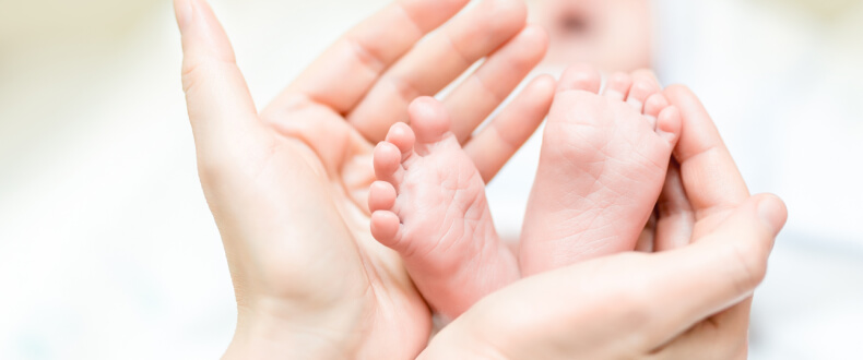 Mother holding feet of newborn baby