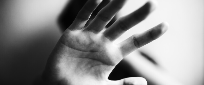 Black and white image of domestic violence victim holding hands up