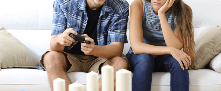Wife waiting by her husband while he is playing video games