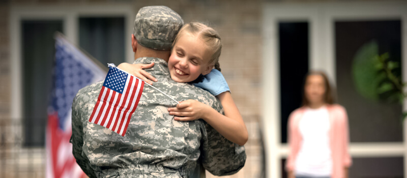 Military Father Hugging Daughter with Mother in background