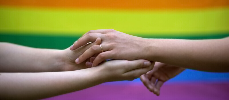 two people holding hands in front of pride flag