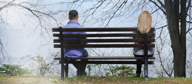 man and woman sitting on opposite ends of a bench