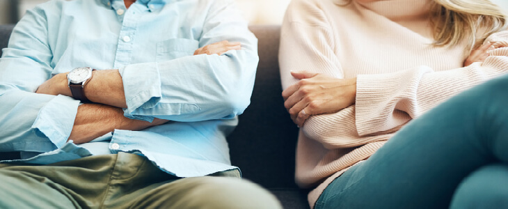 divorced couple sitting down with arms crossed discussing forced sale of marital house