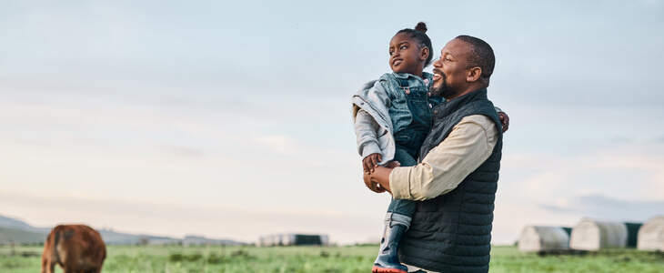 father holding his daughter while looking at the horizon