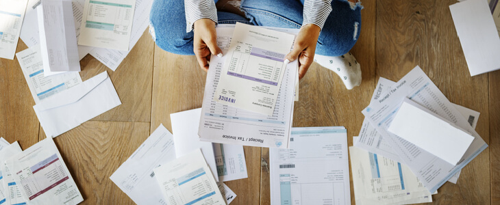 A lady scattering debt documents throughout her floor