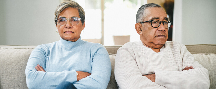 Middle-aged latino couple looking away from each other while sitting on a couch