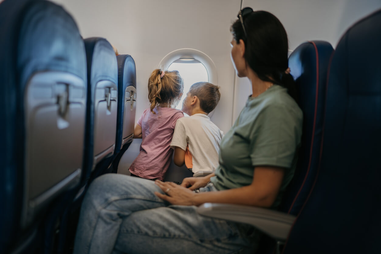 kids looking outside the window on airplane with mom