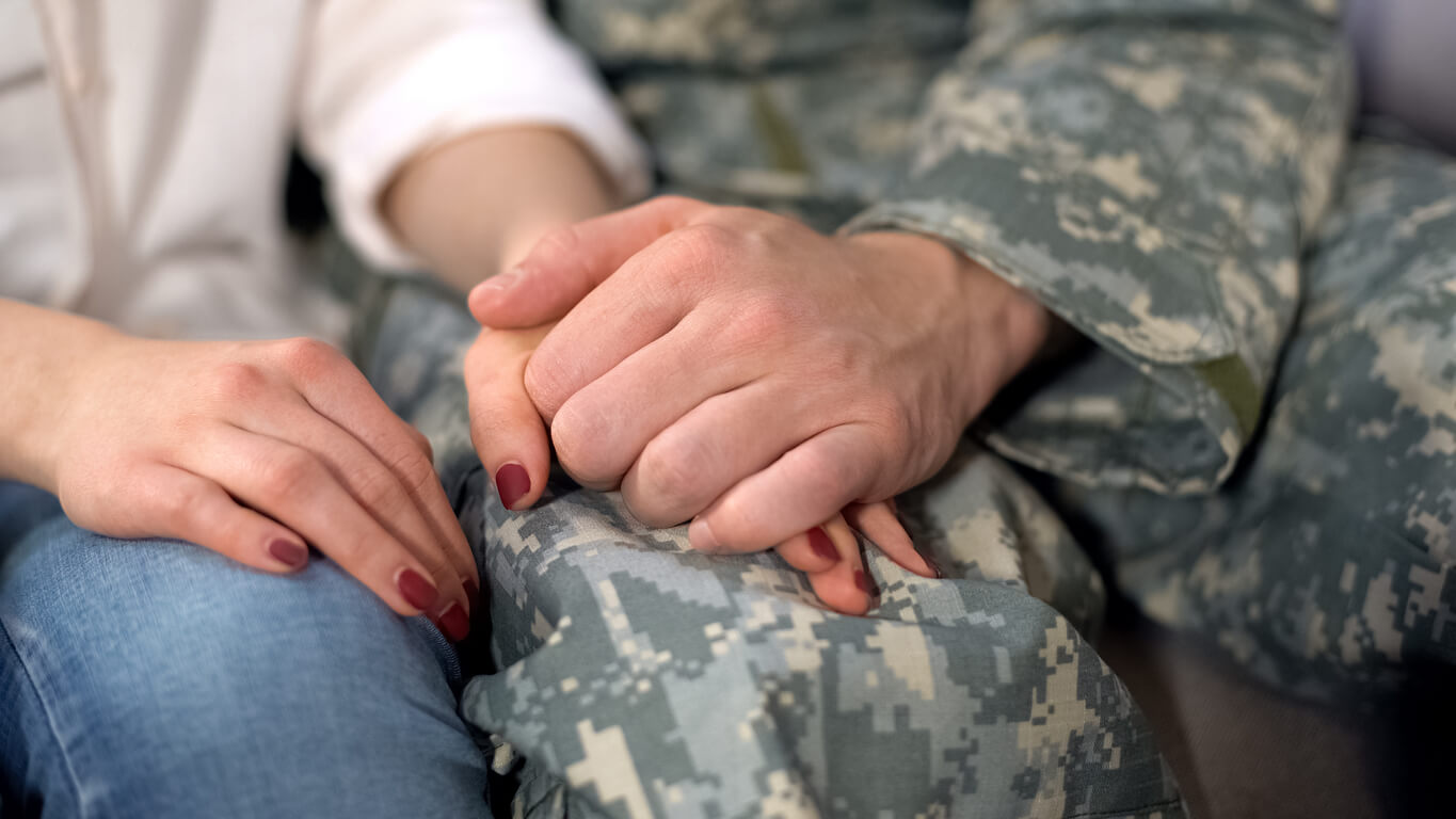 military man holding wife's hand