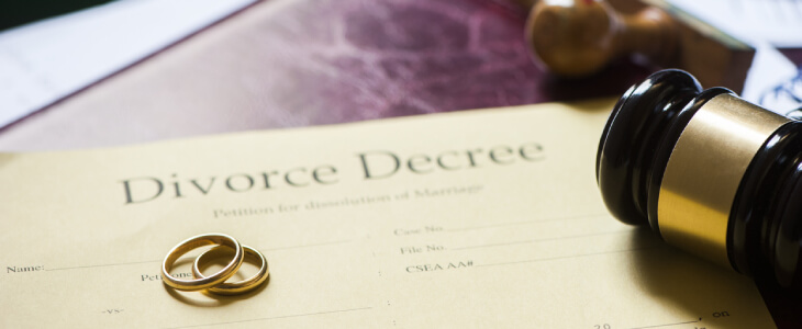 Wedding bands atop paper reading Divorce Decree.