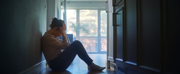 Sad woman sitting on floor resting hands on her head.