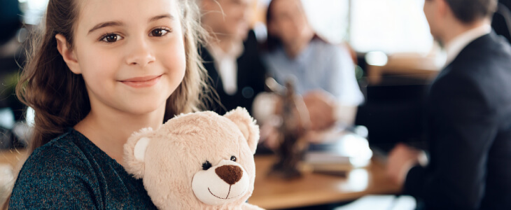 Little girl smiling holding teddy bear.