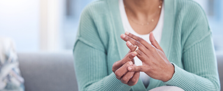 Woman wearing green sweater removing wedding band.