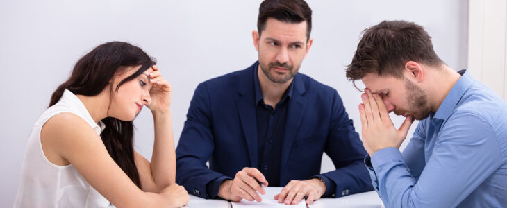 Stressed divorcing couple with mediation attorney.