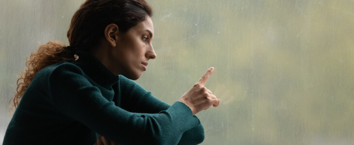 Sad woman sulking by rainy window.