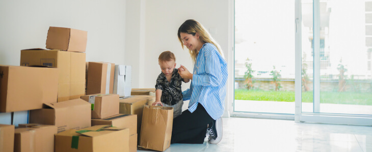 Mother with child unpacking moving boxes in new house after divorce