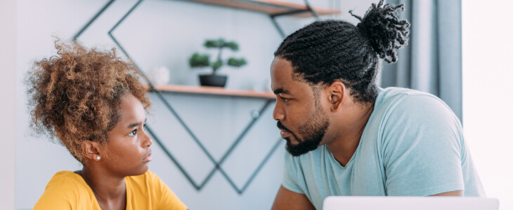 Father and young daughter talking at the table