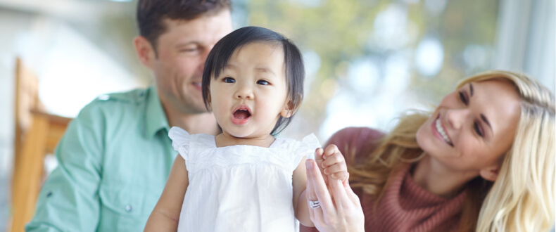 Adopted child with parents smiling