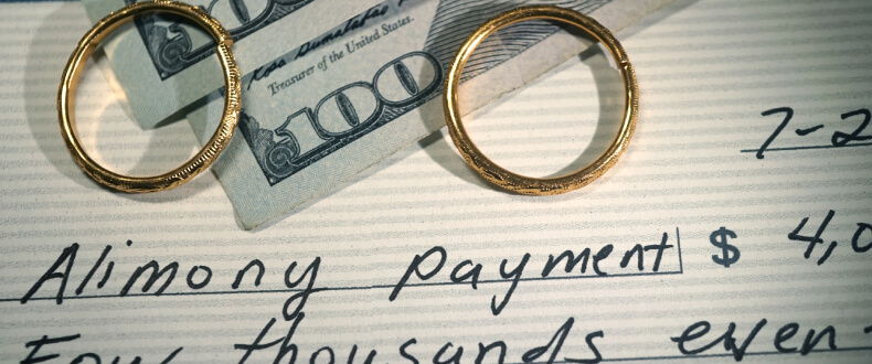 Alimony payment check with wedding rings and cash