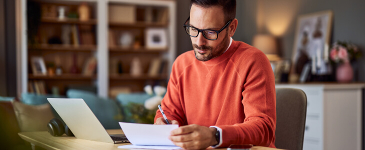 Man sitting at desk with laptop and papers