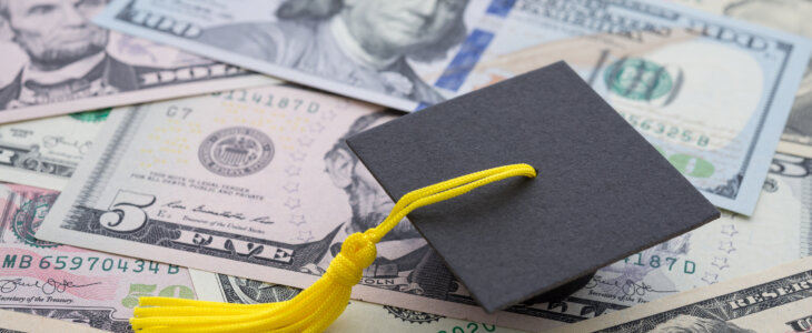 Miniature graduation cap on top of US dollar bills